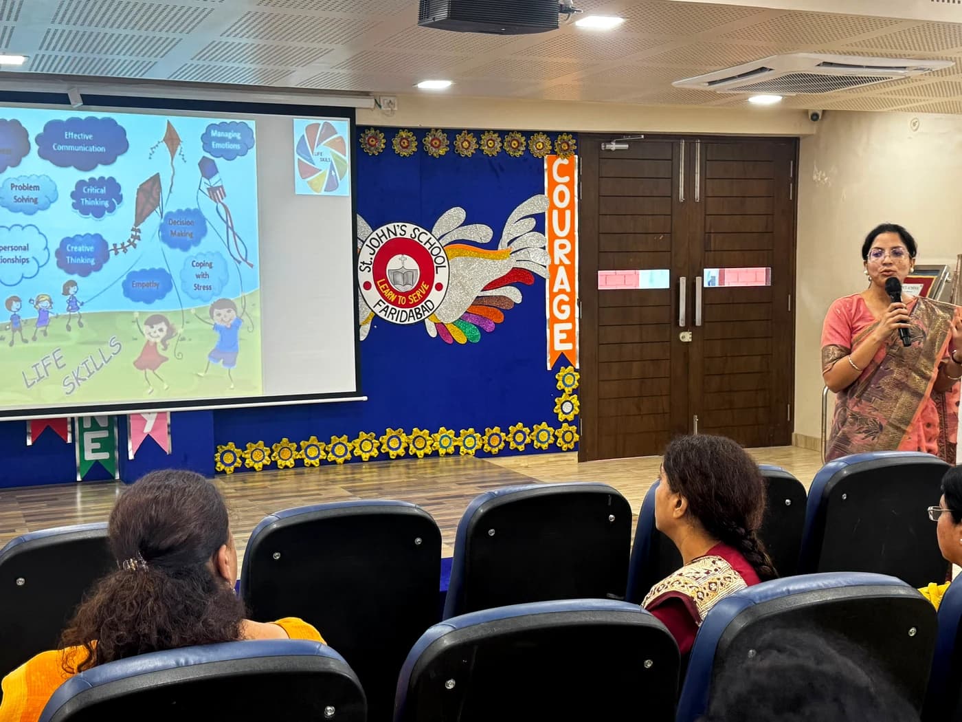 Lamhi on stage with the St. John's School crest in the background